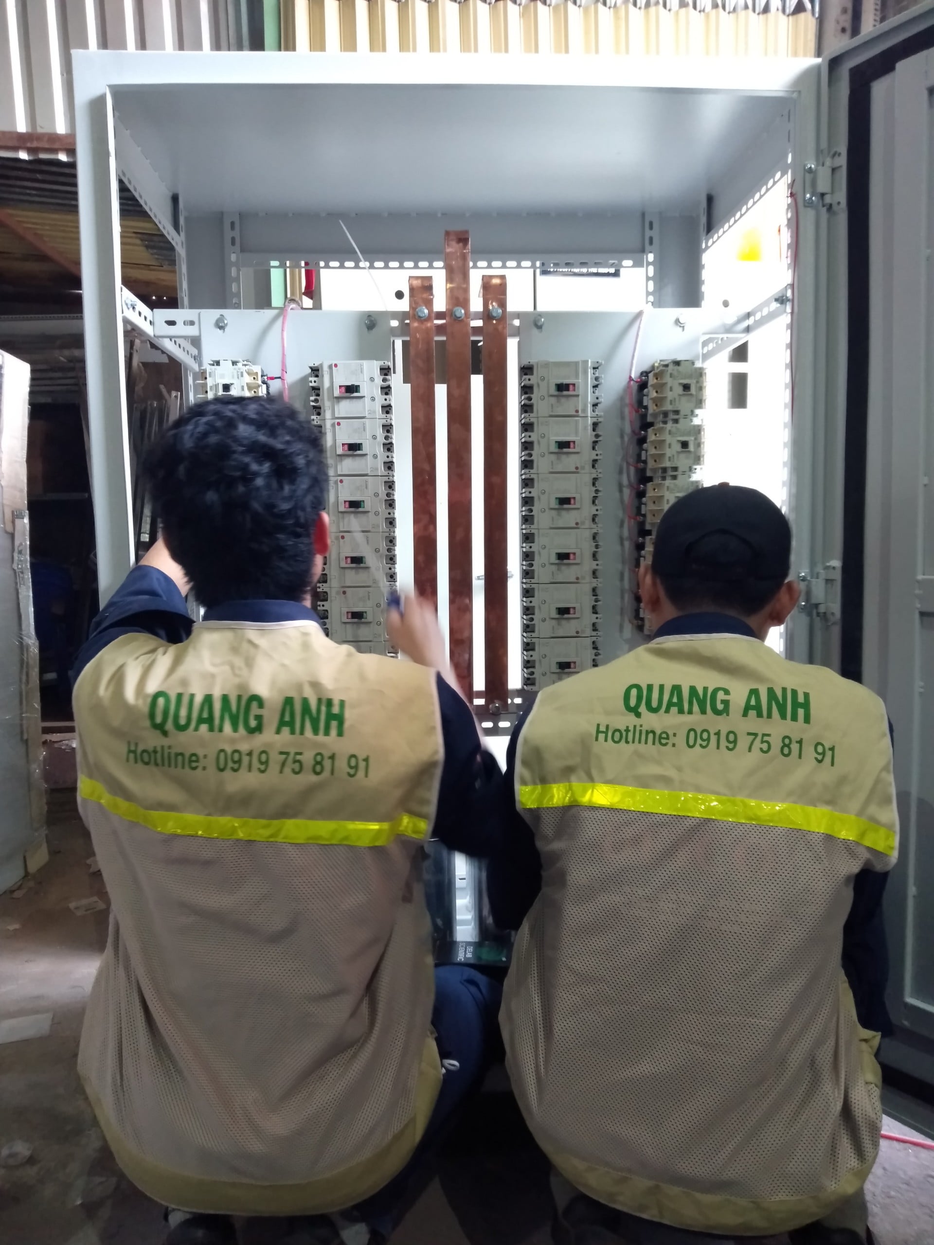 Hai kỹ thuật viên phối hợp lắp ráp và kiểm tra tủ điện trong xưởng Quang Anh